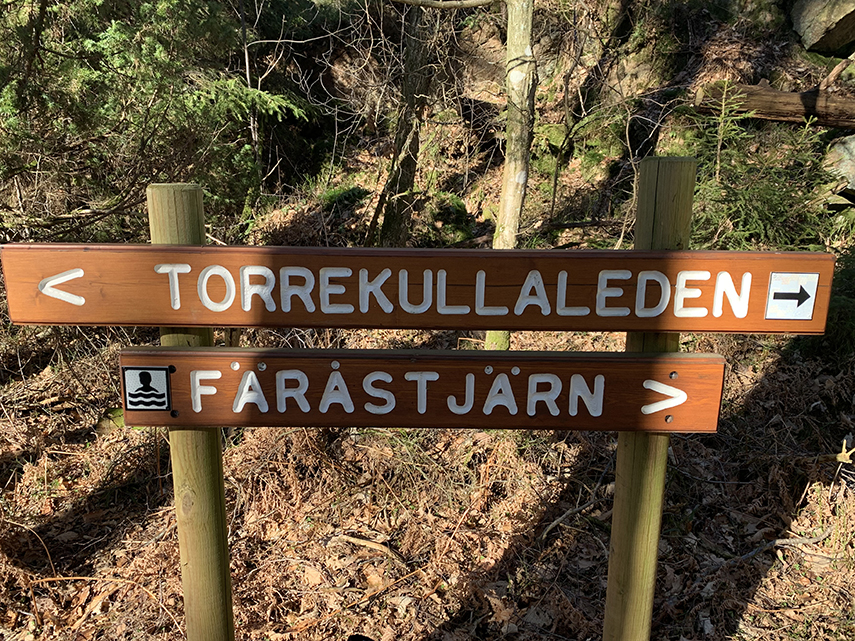 Två skyltar i trä visar vägen till Torrekullaleden respektive Färåstjärn.